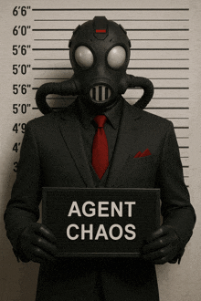 a man in a suit and gas mask holds a sign that says agent chaos
