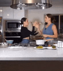 two women are cooking in a kitchen and one of them is wearing glasses