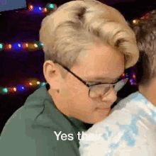 a man wearing glasses is hugging another man and says yes their .