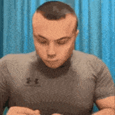 a man wearing a grey under armour shirt looks down at something