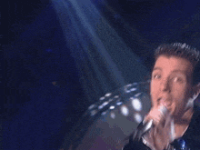 a blurry picture of a man singing into a microphone .