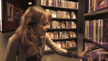 a woman reaches for a book in a library with a book titled " a brief history of the world " on the shelf