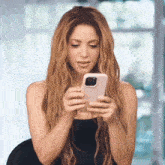 a woman with long blonde hair is holding a cell phone