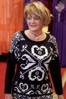 a woman wearing a black and white sweater with hearts and flowers on it