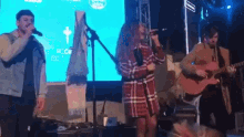 a man playing a guitar and a woman singing on stage