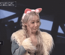 a woman wearing a cat ear headband and a fur coat with the word dreamcatcher on the bottom right
