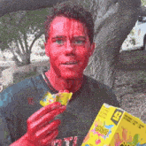 a man with red paint on his face holds a box of gummy bears