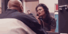 a man and a woman are sitting in front of a mirror talking on a phone .
