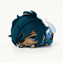 a stuffed animal with blue hair and blue eyes is laying on a white surface