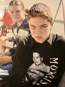 a boy wearing a morris shirt makes a face