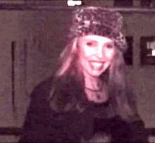 a woman wearing a leopard print hat is smiling in a dark room