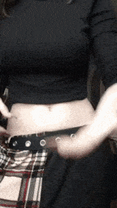 a woman wearing a plaid skirt and a black crop top