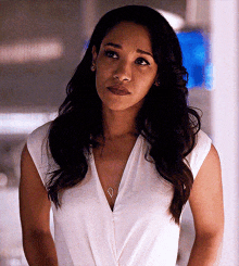 a woman is wearing a white top and a heart necklace
