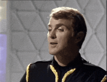 a man in a black uniform with gold ribbons on the sleeves