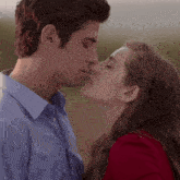 a man and a woman are kissing and the woman is wearing a red top