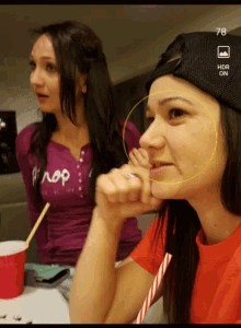 two girls are sitting at a table and one has the number 78 on her shirt