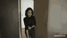 a woman in a black shirt is standing in front of a door that says made in animotica