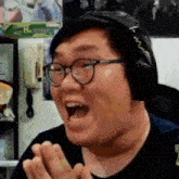 a man with glasses and headphones is making a funny face with his mouth open .