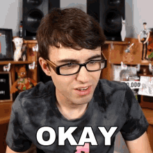 a man wearing glasses and a tie dye shirt has the word okay on his shirt