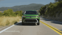 a green volkswagen car is driving down a road
