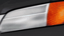 a close up of a car headlight with an orange stripe on the side