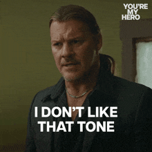 a man says " i don 't like that tone " in front of a you 're my hero logo