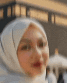 a woman wearing a white hijab is looking at the camera .