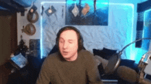 a man wearing headphones is sitting in front of a microphone in a living room .
