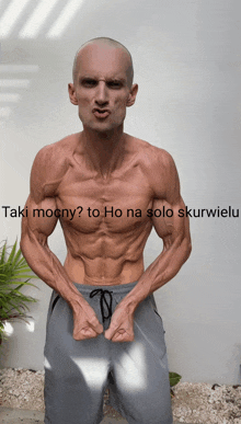 a man without a shirt is standing in front of a white wall with the words taki mocny to ho na solo skurwielu below him