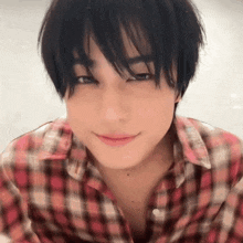 a close up of a young man wearing a plaid shirt