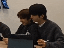 a group of young men are sitting at a table with a laptop and eating ice cream .
