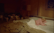 a woman in a pink shirt is sleeping in a bed