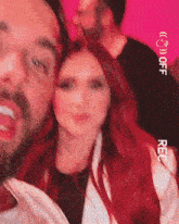 a man with a beard and a woman with red hair are taking a selfie .
