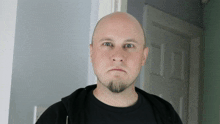 a bald man with a beard wearing a black shirt