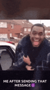 a man is standing next to a car with his tongue out .