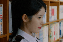 a girl leaning against a bookshelf with a few books on it that say tokyo ghoul