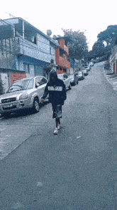 a person walking down a street with cars parked on the side of the road