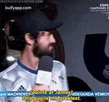 a man is talking into a microphone and says points at james