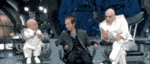 three men in white suits are sitting in chairs in front of a giant eye