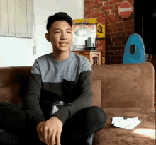 a young man is sitting on a couch with a no entry sign in the background .
