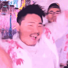 a man with a beard wearing a white shirt with flowers on it is laughing
