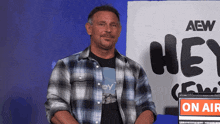 a man in a plaid shirt is standing in front of a sign that says hey crew