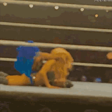 two women are wrestling in a ring and one of them has a blue hair color