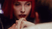 a woman with red hair is holding a man 's hand in front of her face