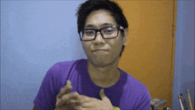 a man wearing glasses and a purple shirt looks at the camera