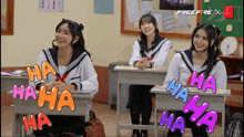 three girls are sitting at desks in a classroom with the words ha ha ha ha ha