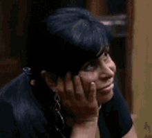 a woman is smiling with her hands on her face and looking to the side .