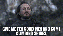 a man with a beard is standing in front of a tree and says give me ten good men and some climbing spikes