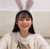 a young girl wearing bunny ears is smiling and looking at the camera .