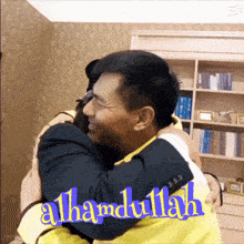 a man in a suit hugging another man in a yellow shirt with the words alhamdulillah above them